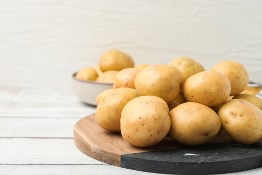Ripe raw young potatoes on white wooden table, closeup. Space for text