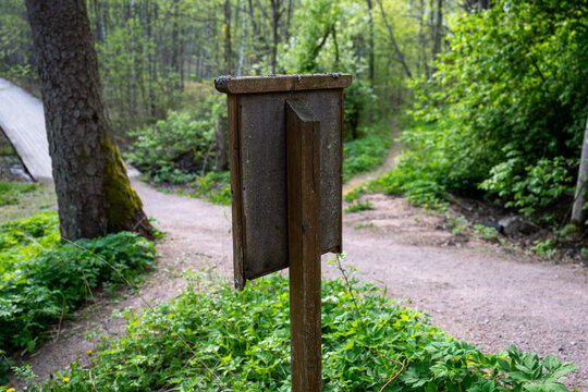 Wooden information board beside hiking trail in green Finnish forest