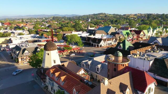 Aerial view of a charming small town with european-style buildings and windmills under a clear blue sky.