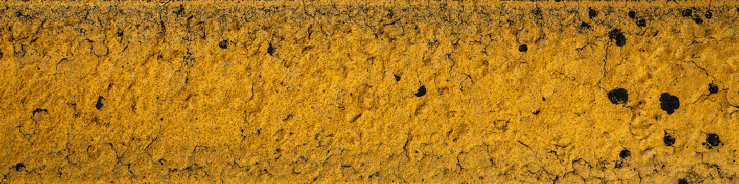Textura de pintura amarilla agrietada sobre asfalto desgastado; fondo abstracto de estilo grunge. Fondo de pantalla.