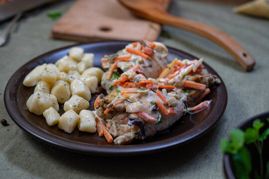 Traditional potato gnocchi served with slow cooked meat stew and vegetables on dark plate