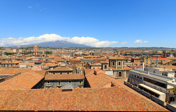 Panoramic view of Italian city rooftops with a snow-capped volcano in the distance
