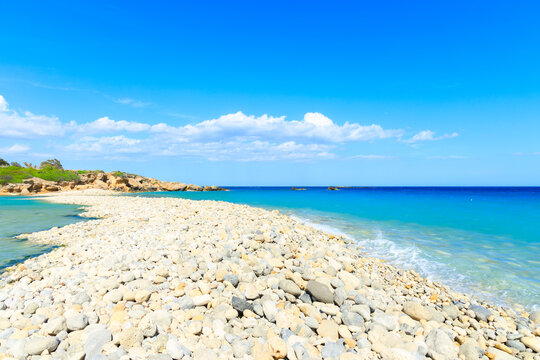 Idyllic pebble beach meets turquoise sea under a bright blue summer sky