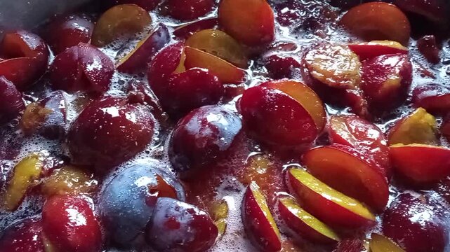 Boiling plum jam being stirred with a spoon close up