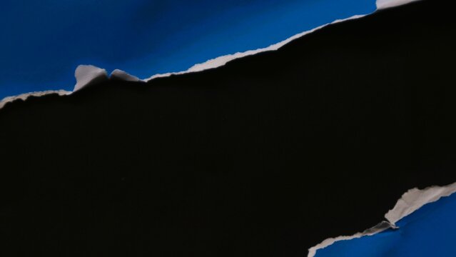 A strip of blue paper torn across the center revealing a black background.