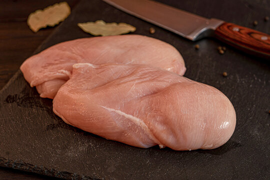 Raw chicken meat cuts including wings, breast fillet and drumsticks on cutting board