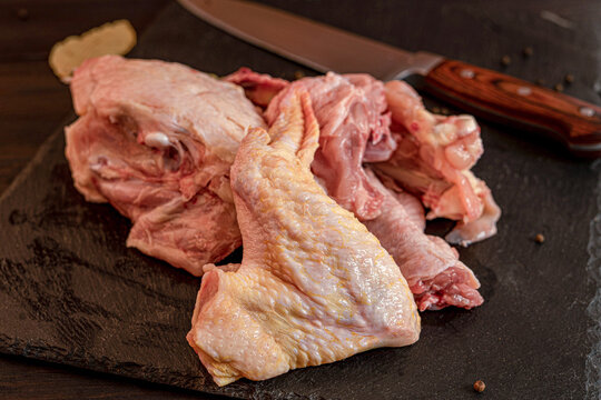 Raw chicken meat cuts including wings, breast fillet and drumsticks on cutting board