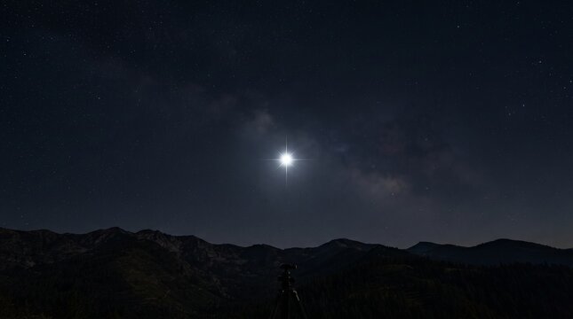 Bright Star Over Mountain Range Under Starry Night Sky With Clouds
