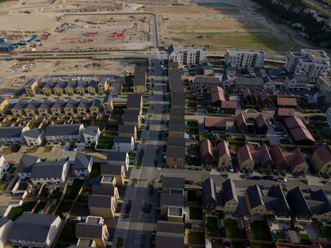 New housing development on a large construction site near Dartford in Kent, UK. Aerial view above the street and newly built residential houses. More houses under construction on an empty land.