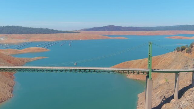 Aerial view of Bidwell Canyon Bridge over Lake Oroville in Northern California during summer drought conditions with low water levels.