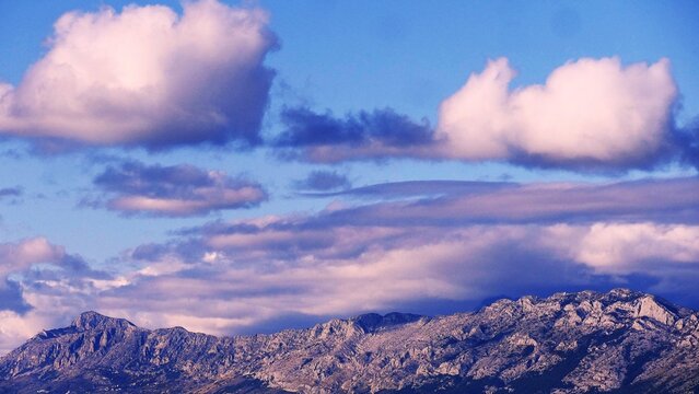 Big mountain with scenic fluffy clouds above with blue horizon, majestic places and destination