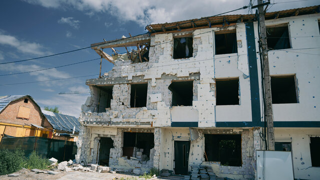 Destroyed residential building damaged by shelling with broken windows and ruined walls during armed conflict