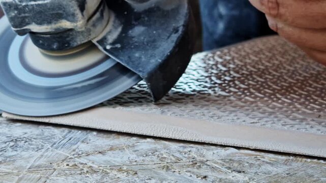 Close-up of the process of cutting the edge of a ceramic tile with a grinder. Diamond disc. Grinding the edge of a tile with an angle grinder. The master processes the edge of the tile with a tool