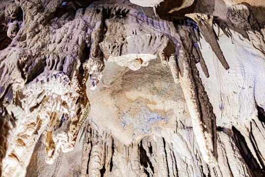 Mineral formations, stalactites and flowstone draperies descending from a rocky ceiling, Pyrenees, France