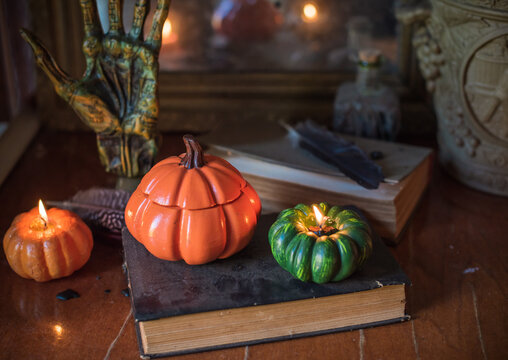 Cozy Halloween home decor with burning pumpkin candles, handmade heart candle, vintage books and mystical props on table