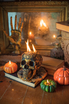 Cozy Halloween home decor with burning pumpkin candles, handmade heart candle, vintage books and mystical props on table