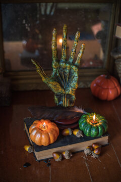Cozy Halloween home decor with burning pumpkin candles, handmade heart candle, vintage books and mystical props on table