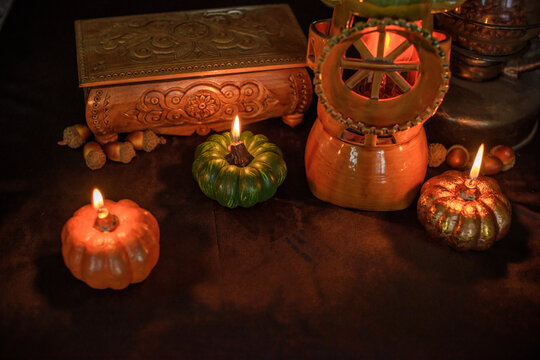 Cozy Halloween home decor with burning pumpkin candles, handmade heart candle, vintage books and mystical props on table