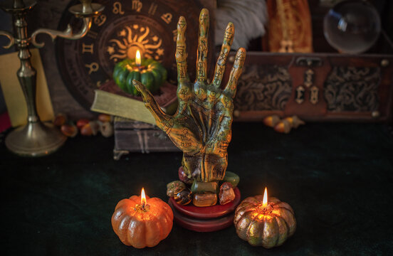 Cozy Halloween home decor with burning pumpkin candles, handmade heart candle, vintage books and mystical props on table