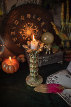 Cozy Halloween home decor with burning pumpkin candles, handmade heart candle, vintage books and mystical props on table