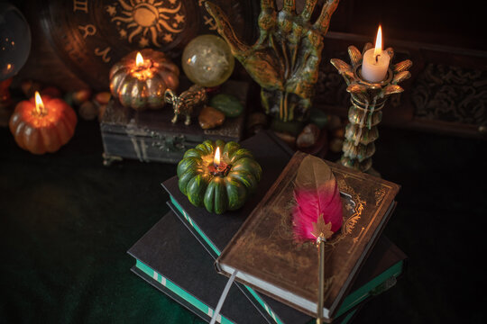 Cozy Halloween home decor with burning pumpkin candles, handmade heart candle, vintage books and mystical props on table