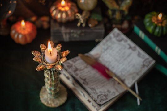 Cozy Halloween home decor with burning pumpkin candles, handmade heart candle, vintage books and mystical props on table