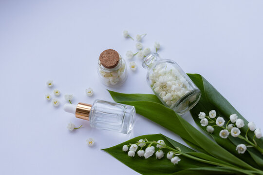 Glass bottle of lily of the valley essential oil with fresh flowers. Copy space.