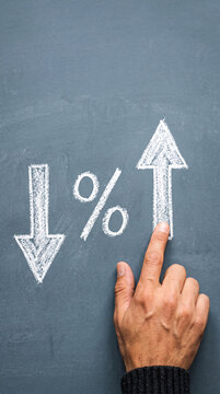 Hand touching arrow pointing up on chalkboard, symbolizing financial growth and positive change, business concept, free space.