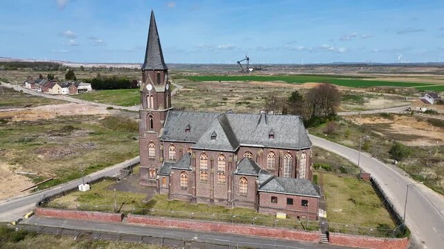 st albanus leonhardus church anchors demolished manheim alt village kerpen germany drone orbit reveals bucket wheel excavator working hambach lignite mine farmhouses wind turbines dot fields horizon