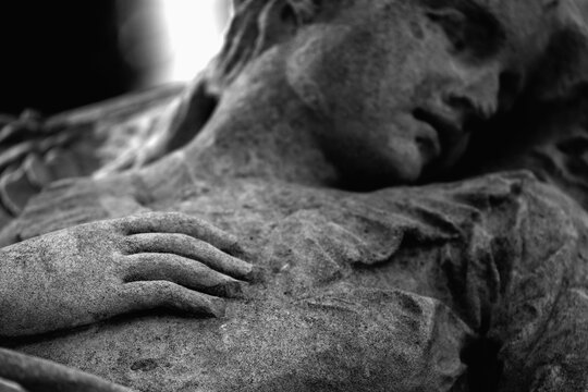 Close-up of an old stone funerary statue symbolizing death, grief, mourning and eternal rest.