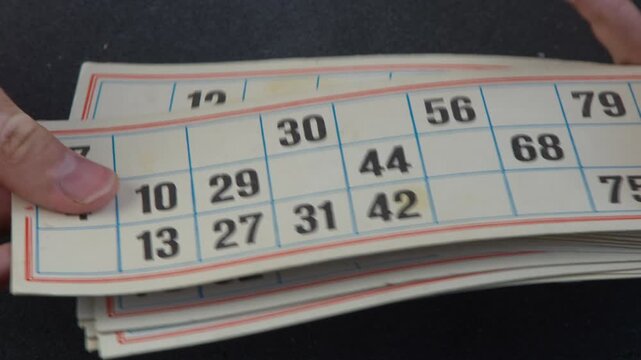 Hands Holding Vintage Lotto Cards with Numbers. Old Bingo game.