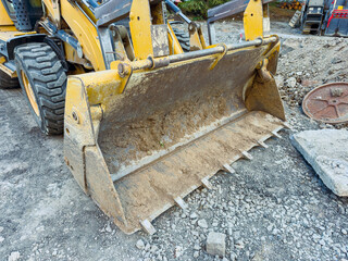 Construction site in a city with a yellow bulldozer working on a gravel surface on a bright sunny day © DSMT