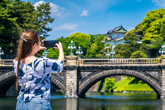 Mujer turista tomando una fotograf&iacute;a con su celular del puente seimon ishibashi, en su paseo por tokio, Jap&oacute;n.