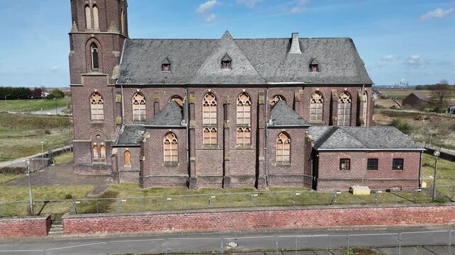 church nave stretches along empty street manheim alt kerpen germany deconsecrated st albanus leonhardus parish boarded gothic windows brick facade sacristy building wall aerial drone altitude