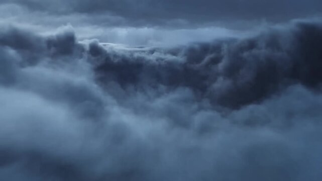 Storm clouds billow and lightning flashes across a dark blue sky during a thunderstorm