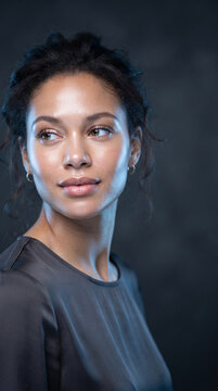 Close-up portrait of a woman with dark wavy hair and light brown eyes, showcasing soft skin and subtle makeup, symbolizing natural beauty and elegance