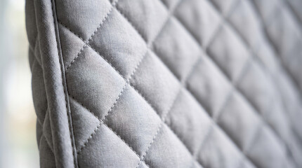 Obraz premium Quilted fabric texture creating a soft padded surface, forming a repetitive diamond pattern, useful for upholstery design, fashion material, and cozy textile backgrounds