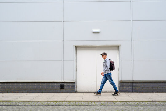 Man Walking Past a Minimalist White Building