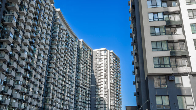 Modern high-rise residential apartment complex with numerous balconies and windows under a clear blue sky, urban architecture