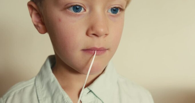 Boy pulling out his loose baby tooth with a string