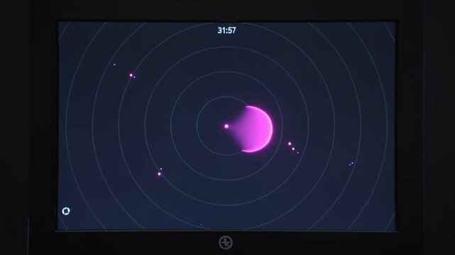 Computer monitor displaying abstract orbital map with glowing purple points in darkness