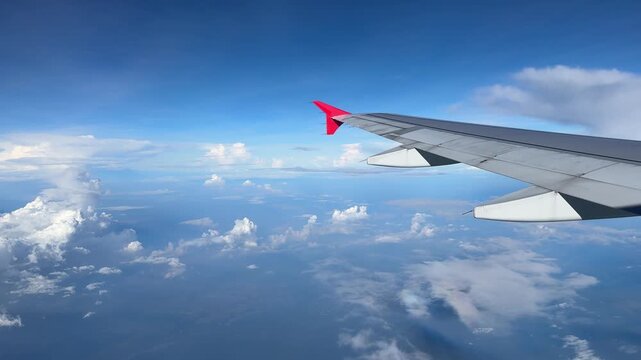 airplane wing on beautiful clouds with the blue sky background, view from window plane. Air Asia's airplane wing