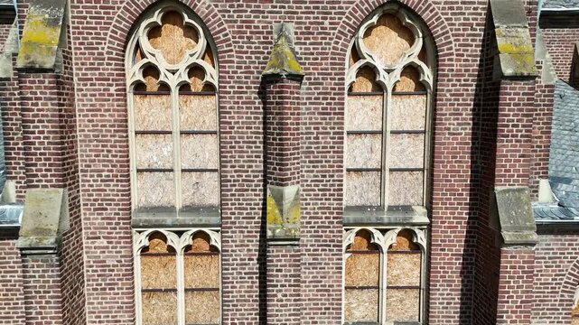 boarded church windows extreme close aerial detail plywood panels gothic tracery brick facade manheim alt kerpen germany deconsecrated parish church empty village surrounds