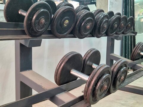 Rack of dumbbells and weight plates in gym close up, representing fitness equipment, strength training, and weightlifting photography.