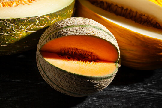 various melons sliced on black wood background
