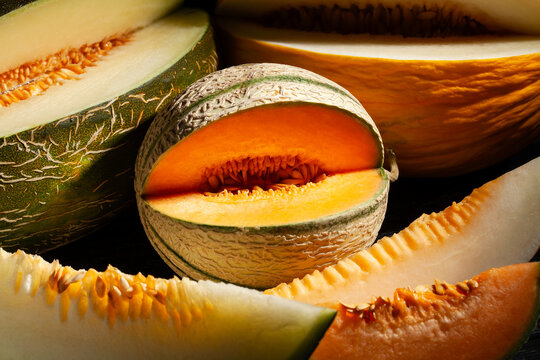 various melons sliced on black background