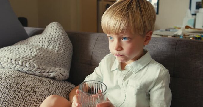Young boy pulling out his own loose baby tooth with a string