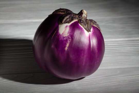 round purple eggplant on grey wood background