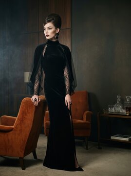 Vintage 1960s gothic glamour fashion model in black velvet evening gown standing in mid-century lounge with copy space