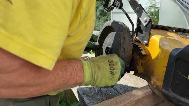 Man repairing yellow lawn mower wheel outdoors during garden equipment maintenance.